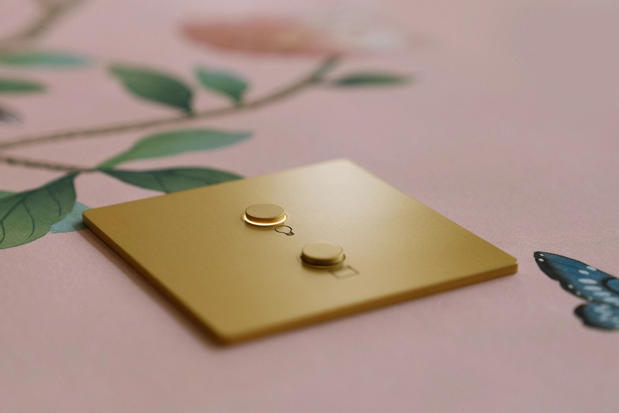 gold metallic Alisse keypad with two backlit push buttons sitting atop a flowery tablecloth