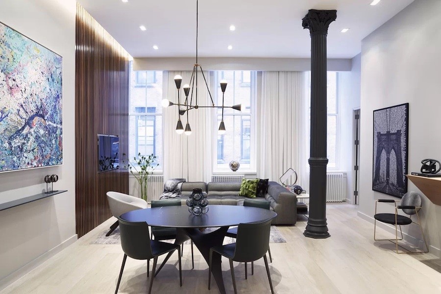 Contemporary kitchen and living space with a round dining table and chairs. A chandelier hangs above it.