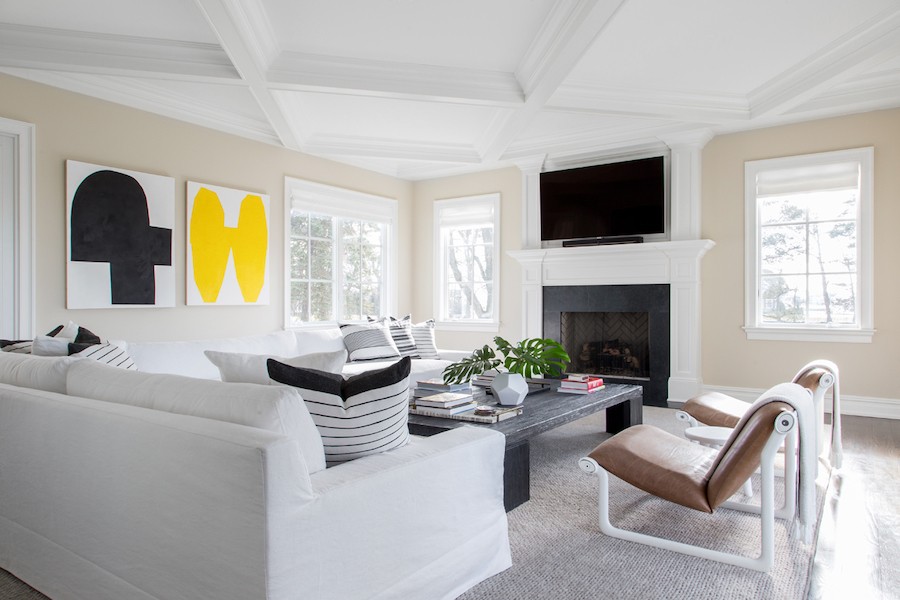 Modern living room featuring abstract art, large TV, and seating area in front of windows with motorized shades.